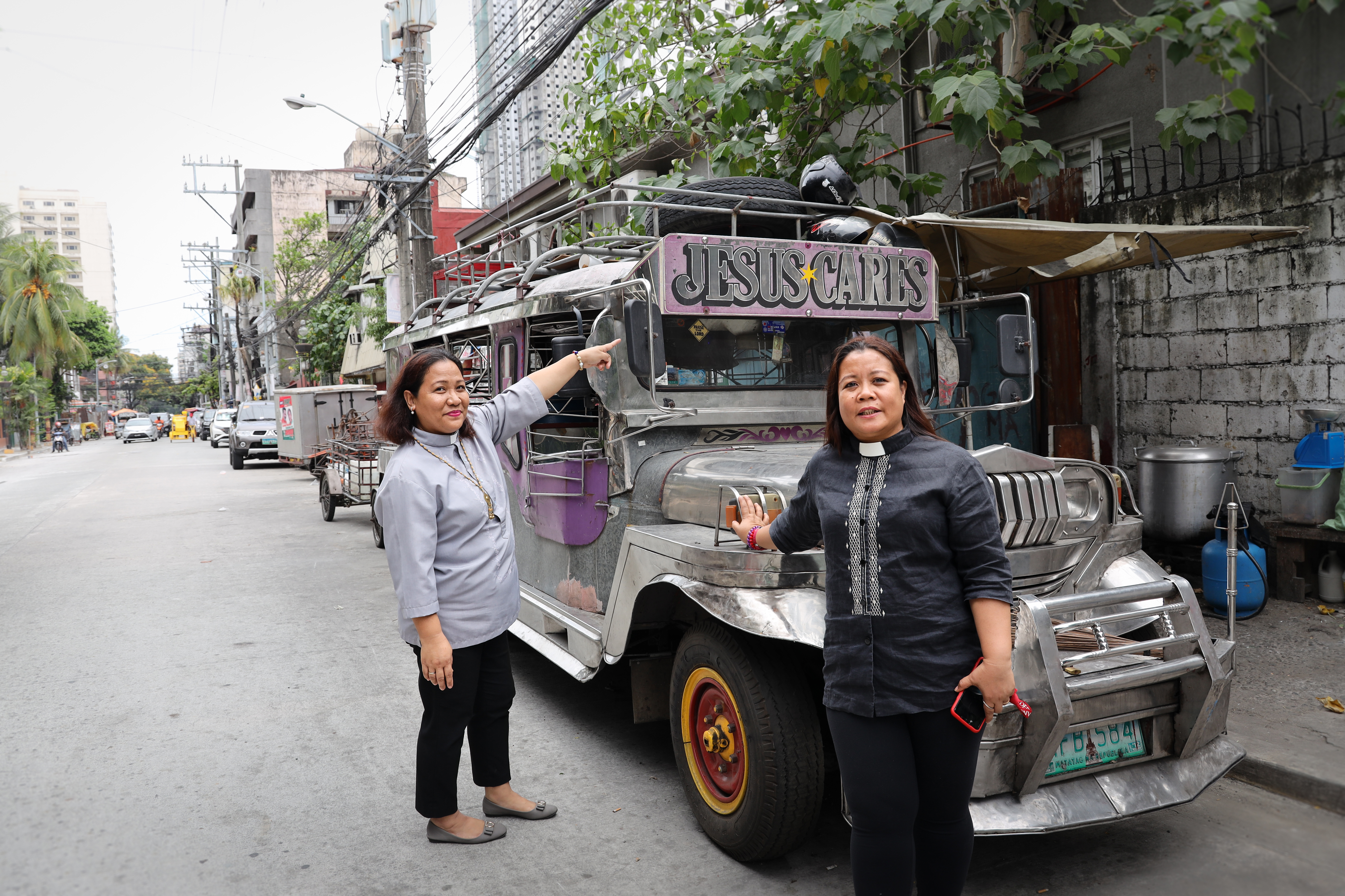 Aileen och hennes kollega framför bilen med texten Jesus cares. 